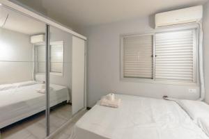 a white bedroom with a mirror and a bed at Centro de Maringá - Must-see! MH703 in Maringá