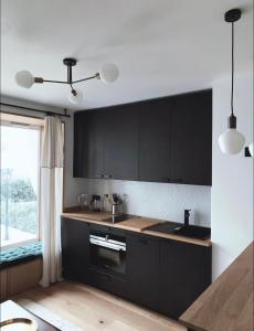 Una cocina con gabinetes negros y un fregadero y una ventana. en Architect Studio Moulin Rouge, en París