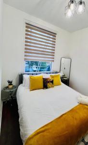 a bedroom with a bed with yellow pillows and a window at Dalston Luxe Studios in London