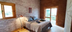 Un dormitorio con una cama en una pared de ladrillos. en Verandas House on Altos do Serrano in São Bento, en Santa Luísa de Baixo