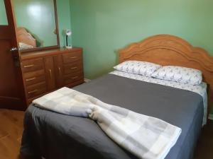 een slaapkamer met een bed met een ladekast en een spiegel bij Markland Cottage Winery in Whitbourne