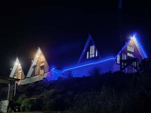 a house with blue lights on it at night at Pines and Beyond cottage in Simāna Basti