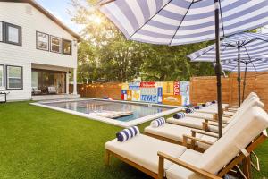 un gruppo di sedie con ombrellone accanto alla piscina di Luxury Downtown Retreat with Pool and Hot Tub, 6Bdr ad Austin