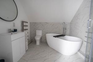 Un baño blanco con bañera y inodoro. en Rookery Park Barns 6, en Carlton Colville