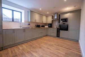 cocina con armarios blancos y suelo de madera en Rookery Park Barns 6, en Carlton Colville