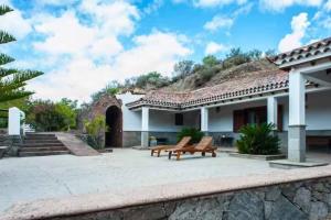 a patio with two benches in front of a house at Casa Rural Cueva del Pastor in Artenara