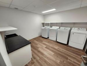 a laundry room with three machines and a counter at Auberge de la traverse in Matane