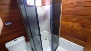 a bathroom with a toilet and a glass shower at CHALÉ HAKUNA MATATA-Vale do capão in Vale do Capao +24 photos