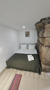 a bed in a room next to a stone wall at Casa do Apeadeiro in Vila Pouca de Aguiar