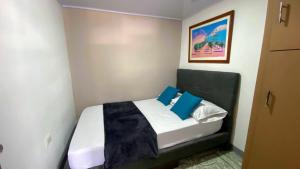 a small bedroom with a bed with blue pillows at Apartamento central en Armenia in Armenia
