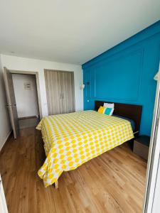 a bedroom with a yellow bed with blue walls and wooden floors at Chic appartement agadir with pool&balcony in Agadir