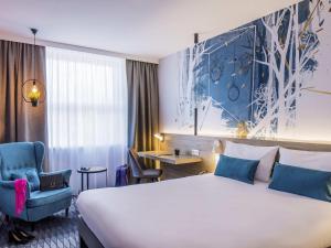 a hotel room with a large bed and a chair at ibis Styles Kraków East in Krakow