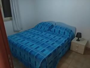 Una cama azul en una habitación con una lámpara en una mesita de noche en Apartment C en Ginosa Marina