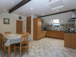 a large kitchen with a table and chairs in a room at Llofft Yr Yd in Porthmadog