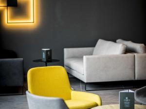 a living room with a yellow chair and a couch at ibis Wels in Wels