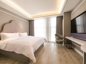 a hotel room with a bed and a flat screen tv at Mercure Ordos Downtown in Ordos