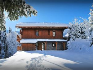una cabaña de madera en la nieve con árboles nevados en Chalet Les Pellys - OVO Network, en Samoëns