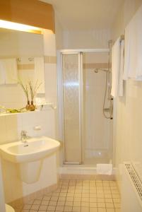a white bathroom with a shower and a sink at Altstadt Hotel Meppen in Meppen