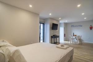 Un dormitorio con una gran cama blanca y una cocina. en Éden Jardim Mar, en Jardim do Mar