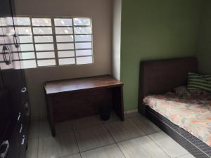 a bedroom with a bed and a desk next to a window at Recanto Alegre in Araguari