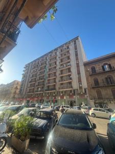 a parking lot with cars parked in front of a large building at La Zisa Luxury Apartment in Palermo