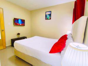 a bedroom with a large white bed with red pillows at Estela Alojamientos in Santo Domingo