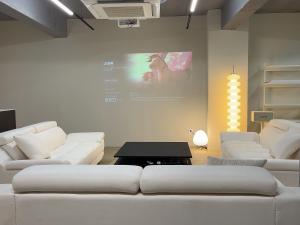 a living room with white couches and a screen at Busan manoah stay hotel in Pusan
