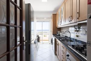 a kitchen with a sink and a large window at Golfinho - Sea view with pool by HD in Quarteira