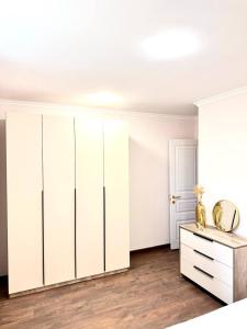 ein weißes Schlafzimmer mit weißen Schränken und einer Kommode in der Unterkunft Aramenc in Gjumri