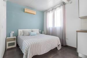 a bedroom with a bed with a striped bedspread and a window at Finca Apartment Near Maspalomas in Artedara +34 photos