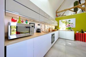 a kitchen with white cabinets and a silver microwave at Magnifique maison d'architecte pour 8 pers avec piscine privée in Roncherolles