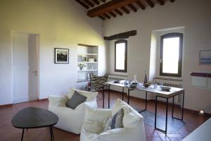 Una sala de estar con sillas blancas y una mesa. en La Loggetta, authentic Tuscany, en Colle Val D'Elsa