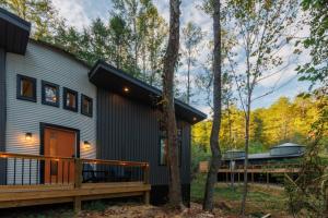 a house in the woods with a porch and a deck at 8 Min to Zip Lines Unique Stay King Bed in Rogers