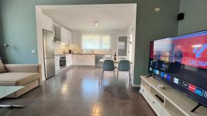 ein Wohnzimmer mit einem großen TV und einer Küche in der Unterkunft Spacious Country House Near Fataga in Artedara