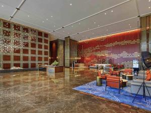 Un vestíbulo con paredes rojas y sillas y un micrófono. en Pullman Huizhou Kaisa, en Huizhou