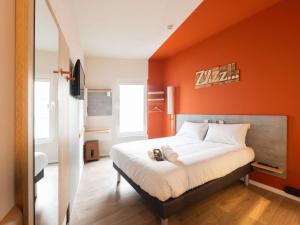 a bedroom with an orange wall with a bed at Ibis Budget Bilbao City in Bilbao