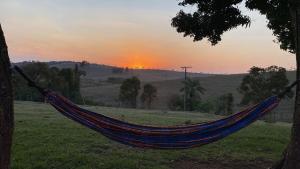 a hammock in a field with the sunset in the background at Fazenda Brasileiro in Passos +7 photos