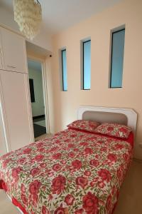 a bedroom with a bed with a red floral bedspread at apartament on vaja pshavela in Tbilisi City