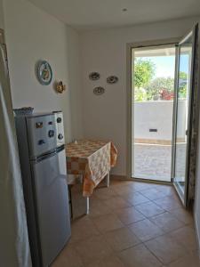 a kitchen with a refrigerator and a table and a sliding glass door at Villa Marinella in Granelli