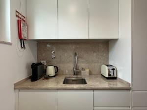 un bancone da cucina con lavello e microonde di WHome Cozy Riverside Apartment in Trafaria a Trafaria