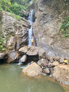zwei Menschen stehen auf Felsen vor einem Wasserfall in der Unterkunft UNDE Village Camp Morogoro in Morogoro