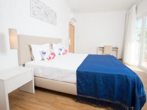 a white bedroom with a large bed with blue sheets at Tavira Monte in Tavira