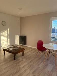 a living room with a table and a red chair at Puesta del Sol Apart in Río Gallegos