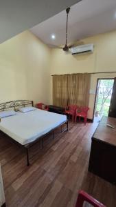 a bedroom with a bed and a living room with red chairs at Furtado's Beach Resort in Benaulim