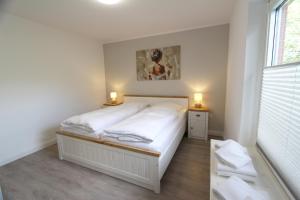 a small bedroom with a bed and two lights on the side at Denghoog- Osetal 10, App 2 in Wenningstedt