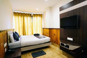 a bedroom with a bed and a flat screen tv at The Fortuna Gangtok in Gangtok
