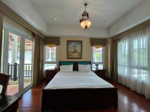 a bedroom with a large bed with windows and a chandelier at 4 bedroom Villa with Private pool at Laguna in Angsana in Ban Thalat Choeng Thale +14 photos