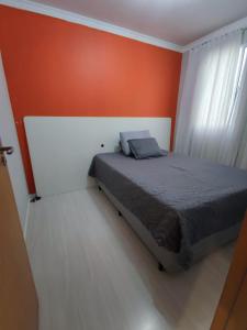 een slaapkamer met een bed met een oranje muur bij Apartamento aconchegante e tranquilo Suzano in Suzano