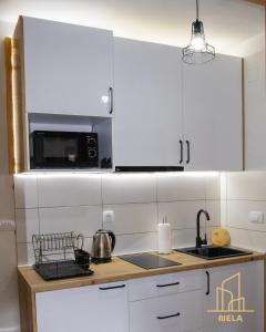 a kitchen with white cabinets and a microwave at Apartman Nela 2 Jahorina in Jahorina