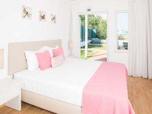 a white bedroom with a white bed with pink pillows at Tavira Monte in Tavira